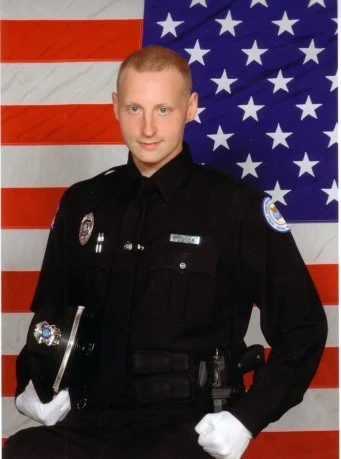 Officer George Ackerman in dress uniform in front of the American flag